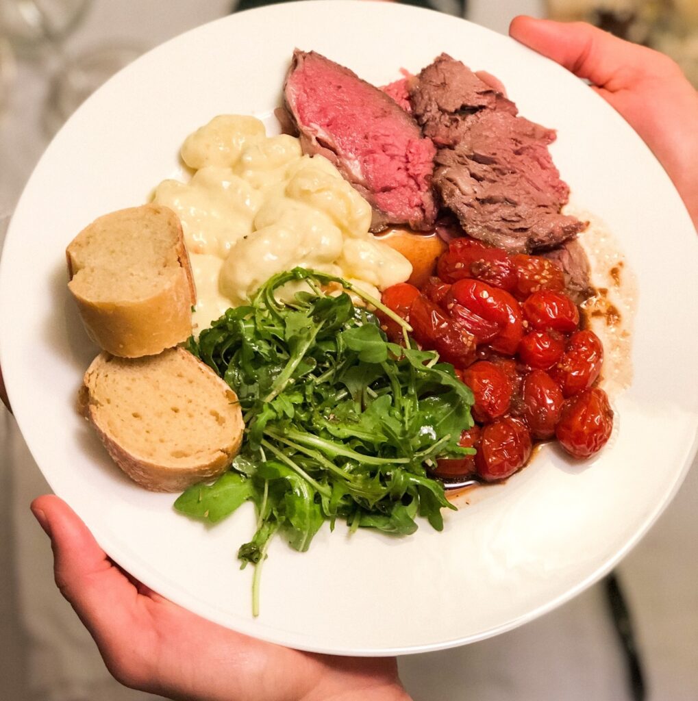 Christmas meal including standing rib roast, Christmas tomatoes, gorgonzola gnocchis, and salad